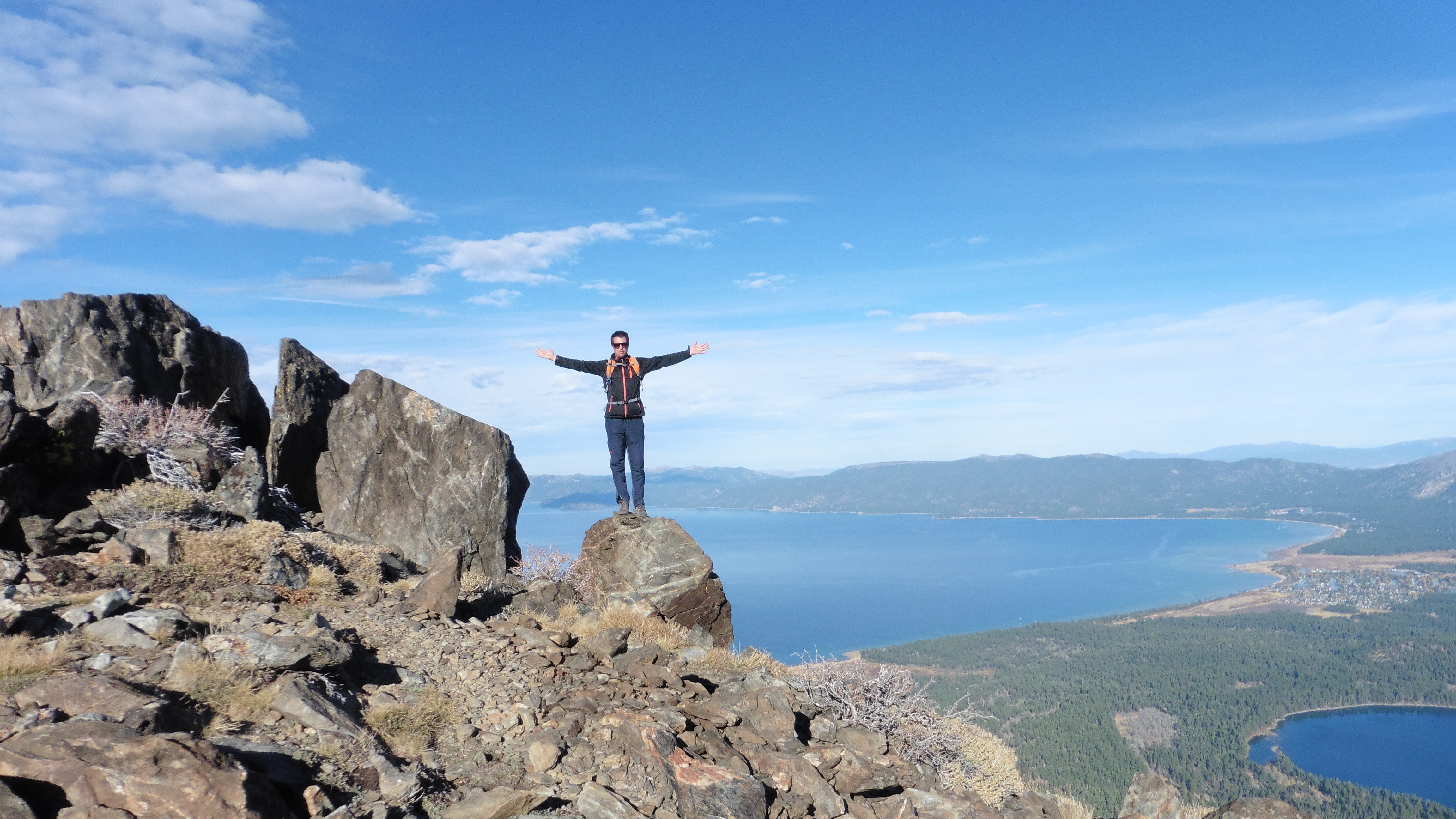honza standing one a mountain arms outstretched by lake tahoe
