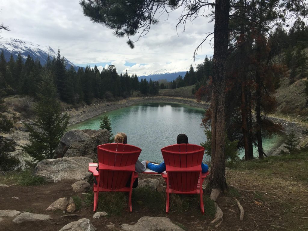 sitting in red chair in front of a lake